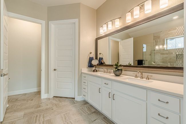 Full bathroom featuring double vanity, tiled shower, and baseboards | Image 31