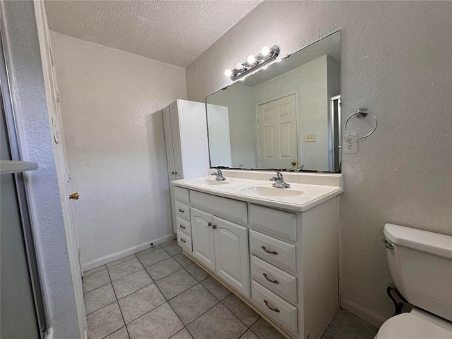 Full bathroom featuring double vanity, tile patterned floors, and a textured ceiling | Image 8