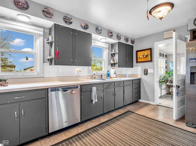 kitchen with a sink, gray cabinets, open shelves, light countertops, and stainless steel dishwasher | Image 18