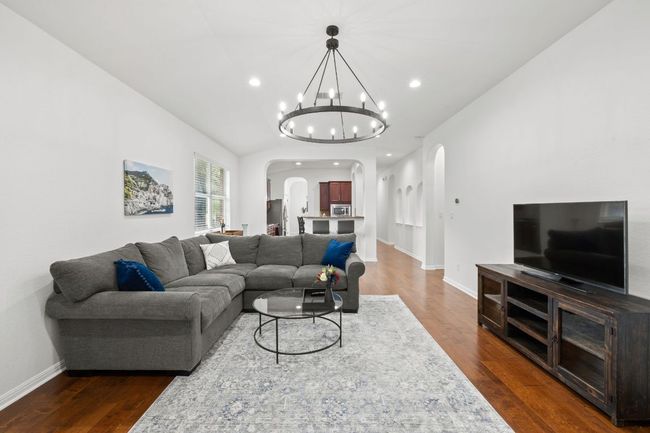 Living area with arched walkways, dark wood-style flooring, a chandelier, and recessed lighting | Image 19