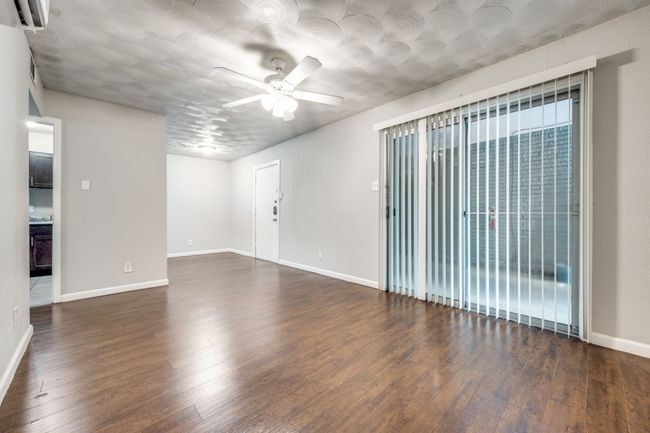 Empty room featuring ceiling fan, dark wood-type flooring, and a wall mounted air conditioner | Image 4