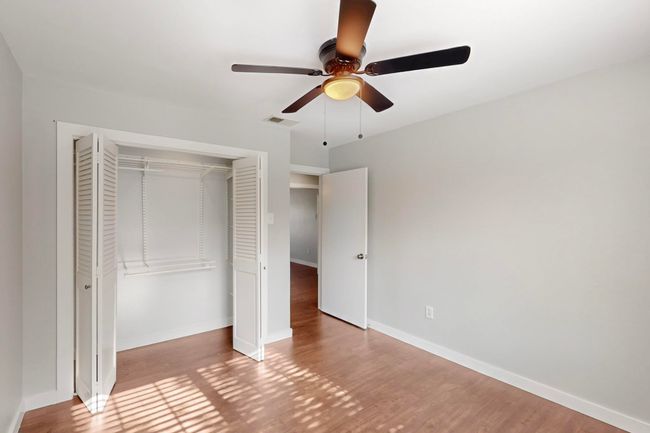 Unfurnished bedroom featuring visible vents, baseboards, a closet, wood finished floors, and a ceiling fan | Image 34