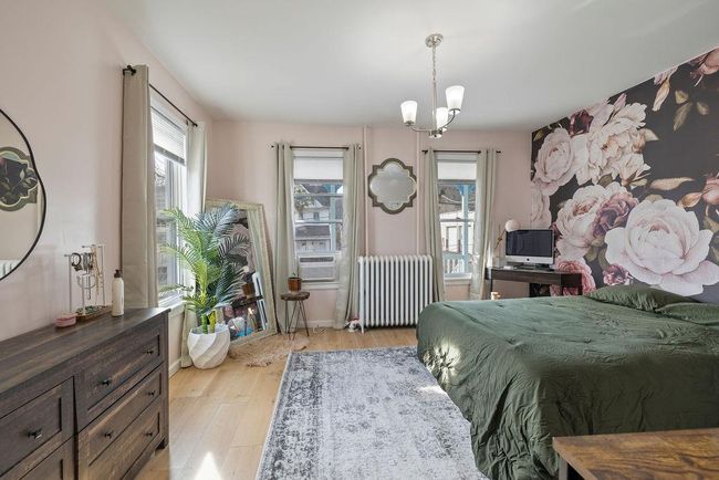 Bedroom with light wood-type flooring, a chandelier, cooling unit, and radiator heating unit | Image 9
