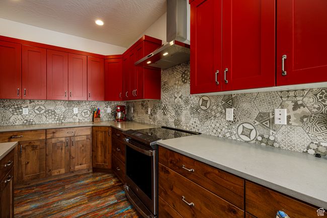 Kitchen with light countertops, wall chimney exhaust hood, red cabinetry, and stainless steel electric range | Image 14