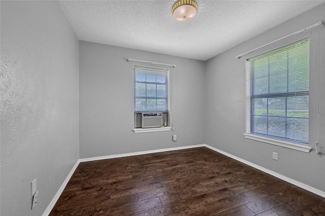 Empty room featuring cooling unit, a textured ceiling, wood finished floors, and baseboards | Image 22