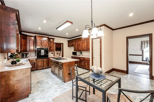 Kitchen featuring black oven, crown molding, stainless steel microwave, gas stovetop, and a chandelier | Image 26