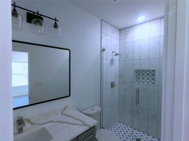 Bathroom featuring toilet, vanity, and a stall shower | Image 12