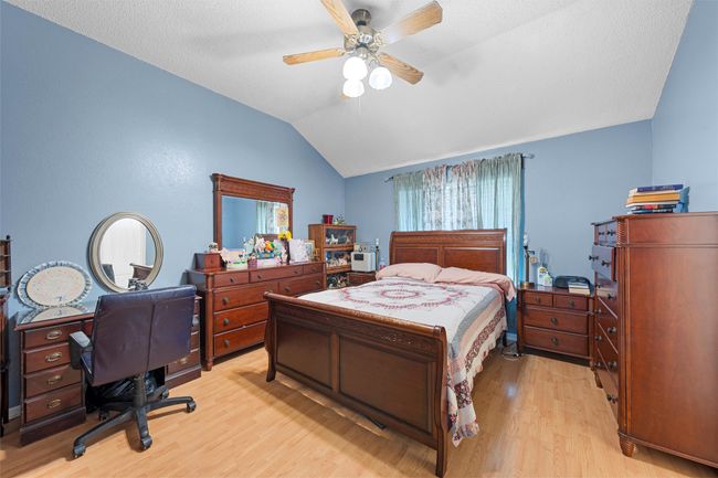 Bedroom featuring vaulted ceiling, light wood-style flooring, a desk, and a ceiling fan | Image 8