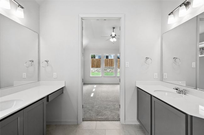 Bathroom featuring ceiling fan, two vanities, tile patterned floors, and lofted ceiling | Image 20