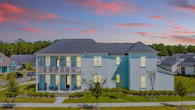 Back house at dusk featuring a balcony, a yard, and a patio | Image 1