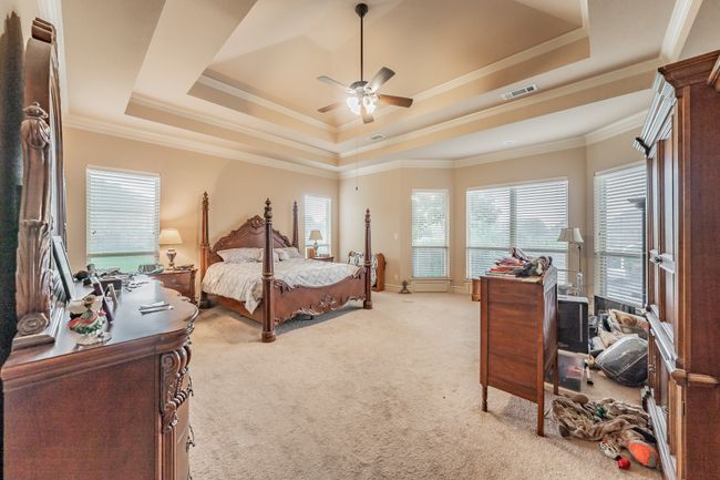 Bedroom with light carpet, a raised ceiling, ornamental molding, and a ceiling fan | Image 22