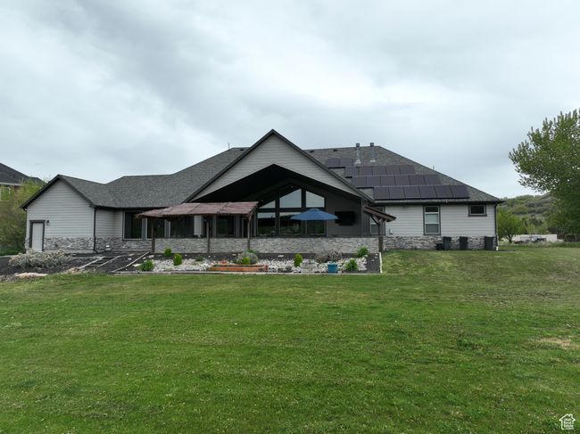 Back of property with a lawn, a shingled roof, and stone siding | Image 59