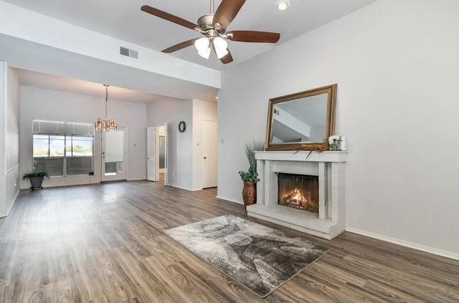 Unfurnished living room featuring wood finished floors, a chandelier, a fireplace, and ceiling fan | Image 15