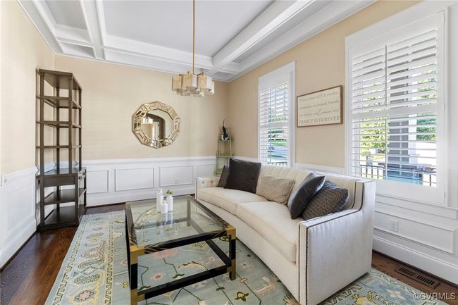 Living room featuring a chandelier, wainscoting, dark wood-type flooring, beam ceiling, and coffered ceiling | Image 7