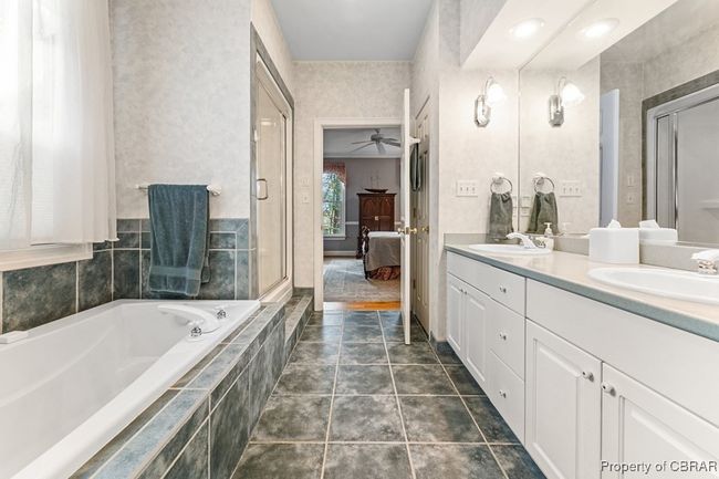 Ensuite bathroom featuring double vanity, a bath, ceiling fan, and a shower with door | Image 29