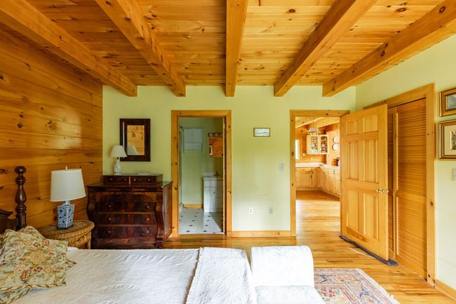 Bedroom featuring light wood-style flooring, wood ceiling with exposed beams, connected bathroom, and baseboards | Image 13