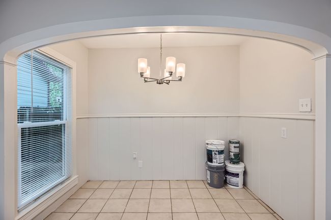 Unfurnished dining area with an inviting chandelier, light tile patterned floors, arched walkways, and wainscoting | Image 15