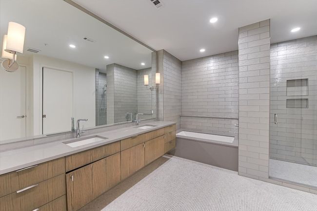 Bathroom featuring a garden tub, a sink, double vanity, and a stall shower | Image 9