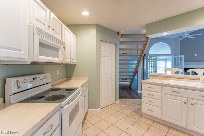 Kitchen featuring white appliances, recessed lighting, light tile patterned floors, light countertops, and white cabinets | Image 11