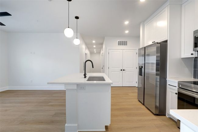 Kitchen featuring stainless steel appliances, a sink, recessed lighting, light wood finished floors, and a kitchen island with sink | Image 5