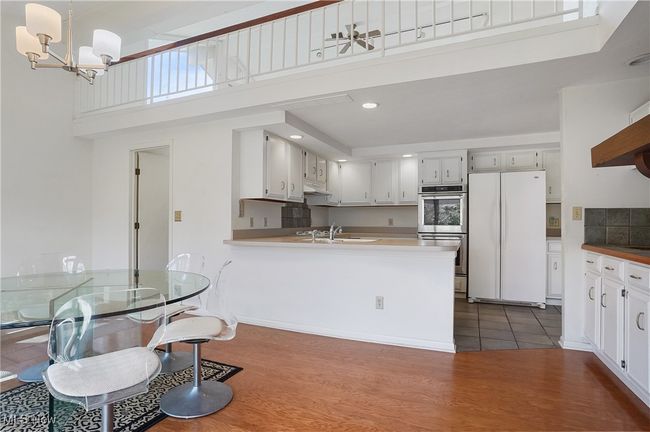 Kitchen featuring dark wood finished floors, double oven, an inviting chandelier, a sink, and freestanding refrigerator | Image 17