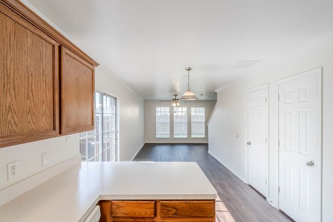 Kitchen featuring a peninsula, ornamental molding, brown cabinets, light countertops, and dark wood-type flooring | Image 8