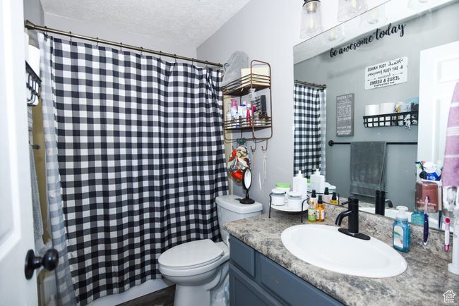 Bathroom featuring toilet, a textured ceiling, a shower with shower curtain, and vanity | Image 26