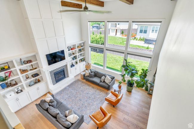 Living room with plenty of natural light, a tiled fireplace, light wood-style flooring, ceiling fan, and beam ceiling | Image 40