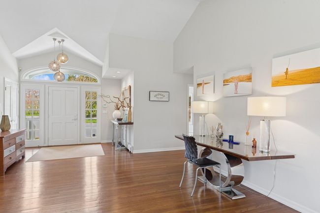 Foyer entrance featuring a notable chandelier, high vaulted ceiling, wood finished floors, and baseboards | Image 19