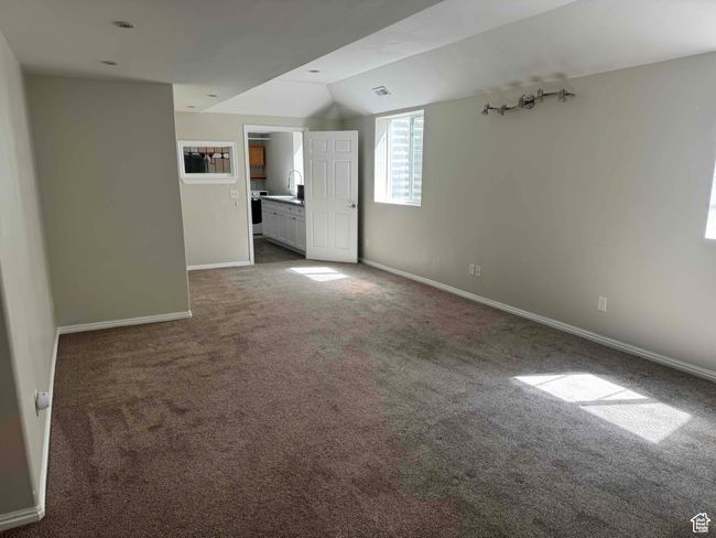Unfurnished living room with carpet floors, lofted ceiling, baseboards, and a sink | Image 20