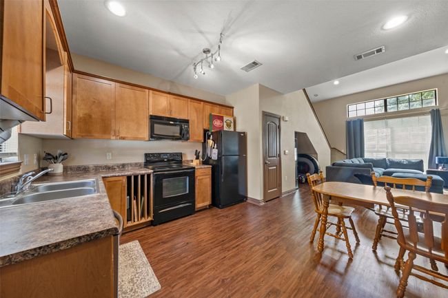 Kitchen featuring black appliances, dark wood-type flooring, recessed lighting, open floor plan, and brown cabinets | Image 5