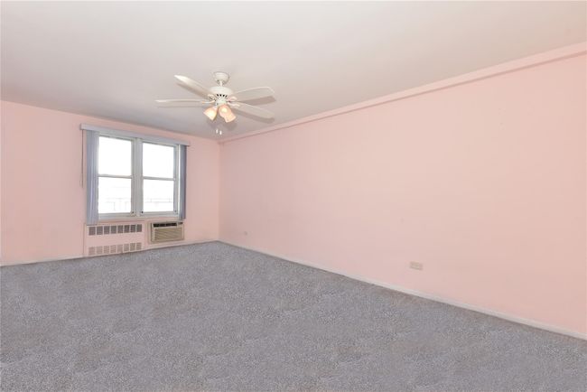 Carpeted spare room with radiator, ceiling fan, and a wall mounted AC | Image 16