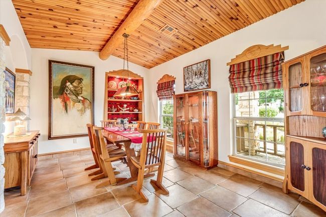 Dining space with healthy amount of natural light, light tile patterned floors, wood ceiling, and baseboards | Image 11