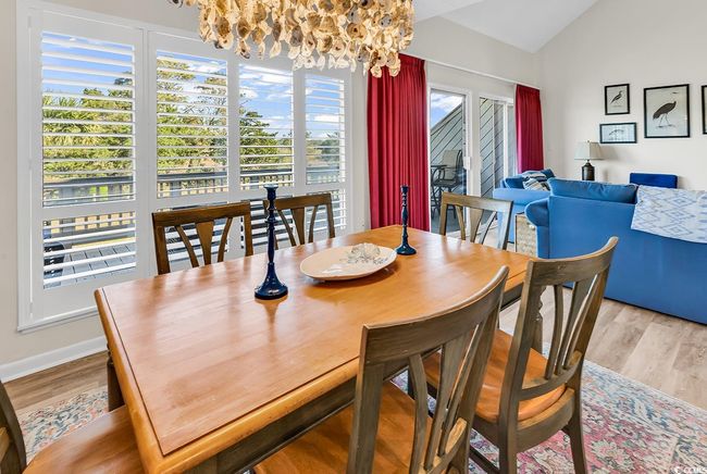 Dining space with baseboards, lofted ceiling, wood finished floors, and a notable chandelier | Image 10