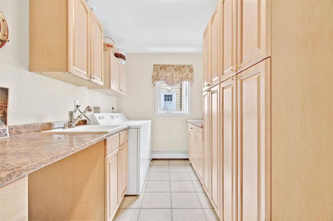 Laundry room featuring cabinet space, separate washer and dryer, and light tile patterned floors | Image 24