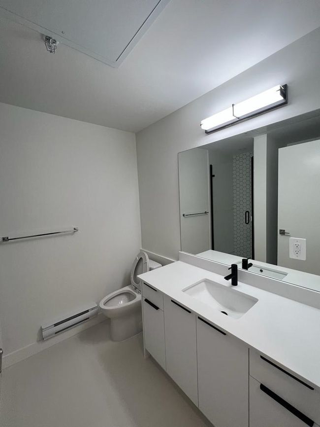 Bathroom with toilet, vanity, and a baseboard radiator | Image 7
