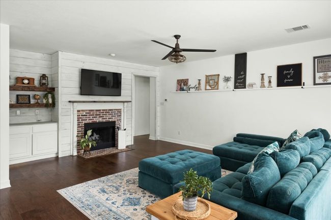 Downstairs living room is anchored by fireplace and open to the kitchen, ideal entertaining home! | Image 9