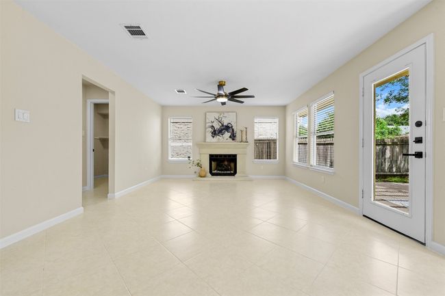 Unfurnished living room featuring a ceiling fan, light tile patterned floors, and a glass covered fireplace | Image 14