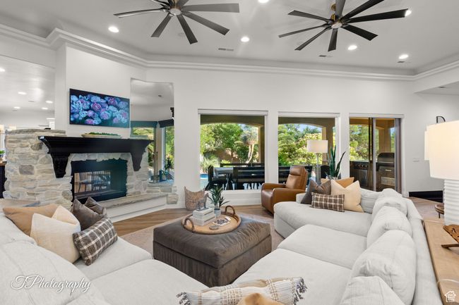 Living room featuring a ceiling fan, ornamental molding, a fireplace, recessed lighting, and wood finished floors | Image 22