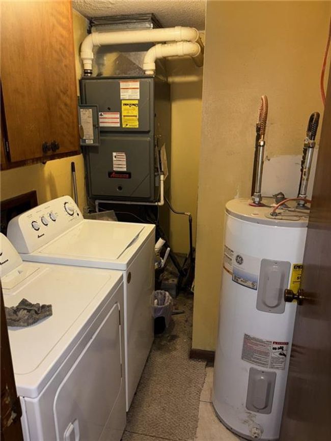 Laundry area featuring electric water heater, washer and clothes dryer, and cabinet space | Image 17