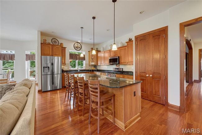Kitchen with stainless steel appliances, light wood-style floors, open floor plan, a kitchen island, and a kitchen bar | Image 17
