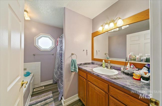 Bathroom featuring vanity, wood finished floors, a textured ceiling, a bath, and curtained shower | Image 34