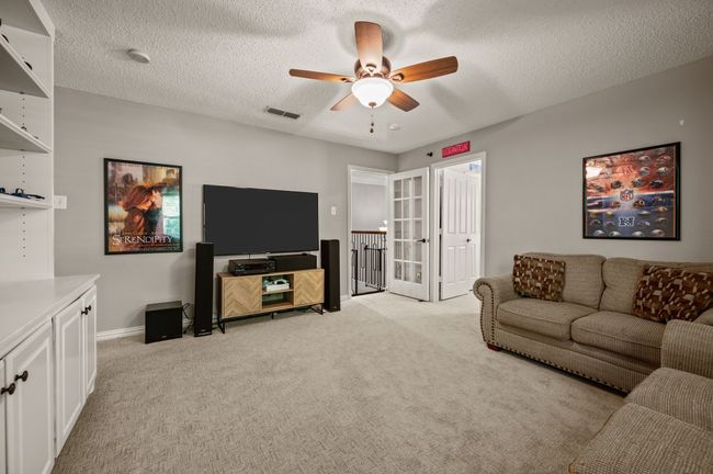 Living room with light colored carpet, a textured ceiling, and a ceiling fan | Image 24
