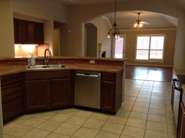 Kitchen featuring arched walkways, light tile patterned floors, ceiling fan, dishwasher, and a sink | Image 7