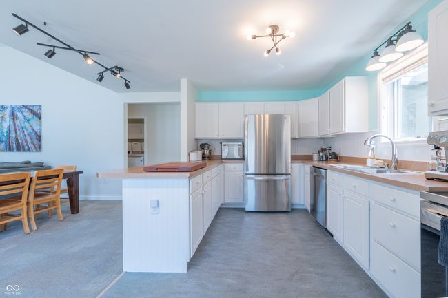 kitchen featuring white cabinets, stainless steel appliances, light countertops, a sink, and a peninsula | Image 8
