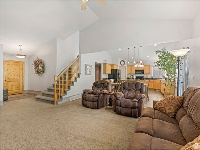 Living area featuring light carpet, stairway, ceiling fan, vaulted ceiling, and recessed lighting | Image 11