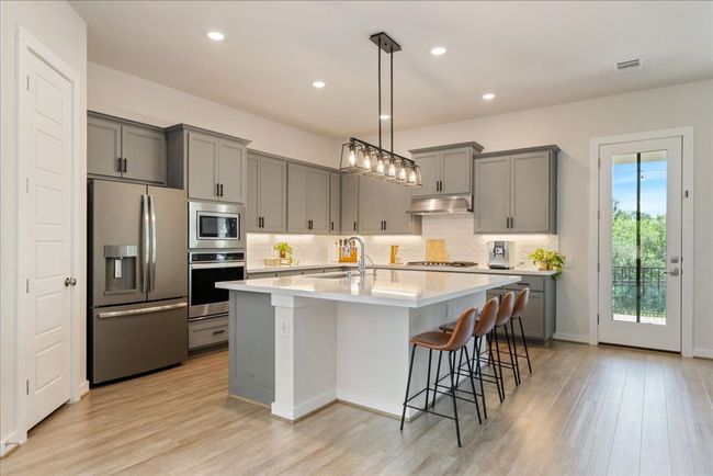 Kitchen featuring gray cabinetry, under cabinet range hood, a sink, and appliances with stainless steel finishes | Image 8