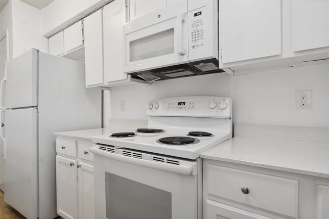 Kitchen with light countertops, white appliances, and white cabinetry | Image 7