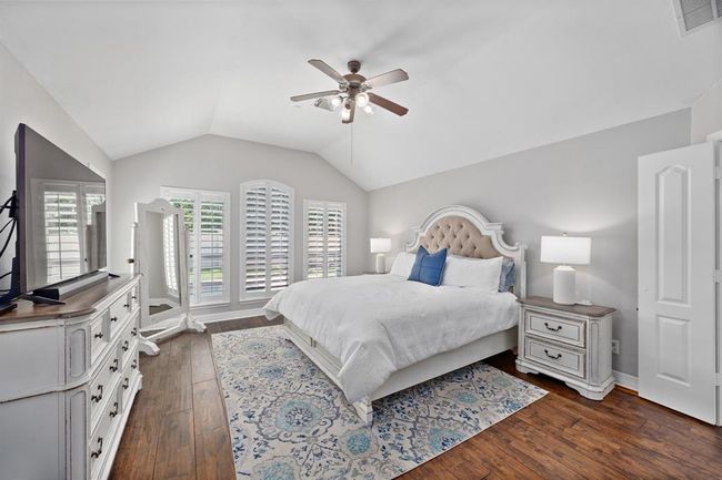 Oversized primary suite is tucked in the back of the home with neutral paint, plantation shutters, and access to the backyard. | Image 24