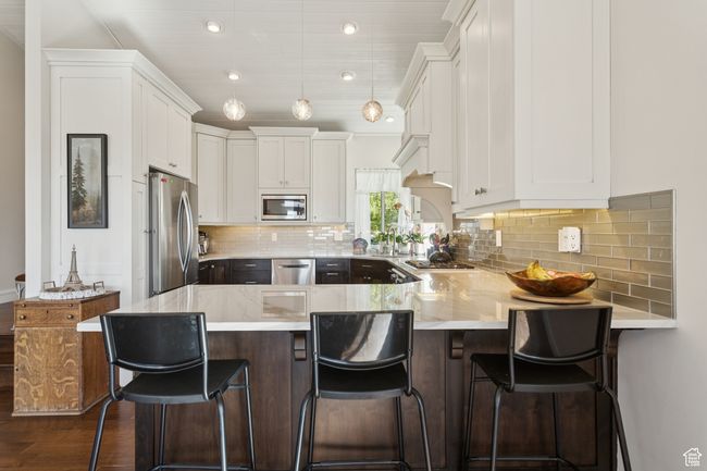 Kitchen featuring appliances with stainless steel finishes, a peninsula, white cabinetry, dark wood-style floors, and recessed lighting | Image 6